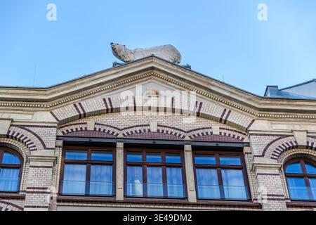 Nahaufnahme einer Steinskulptur eines Eisbären auf dem Giebel eines Gründerzeit-Gebäudes mit Klinkerziegel und Natursteinfassade. Leipzig, Sachsen, Deutschland Stockfoto