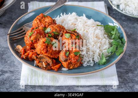 Scharfe Schweinefleischbällchen in Tomatensauce mit Basmatireis Stockfoto