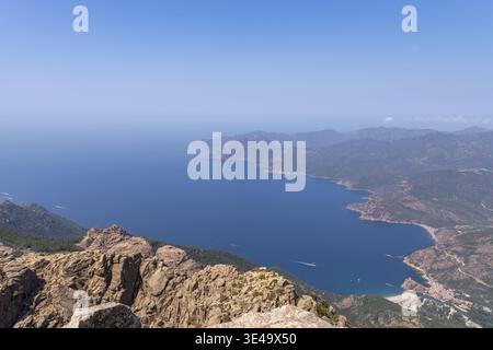 Hoher Blick auf das atemberaubende Mittelmeer, die zerklüfteten Berge und das kleine Küstendorf in Korsika, Frankreich Stockfoto