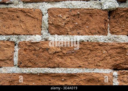 Raue, strukturierte orangefarbene Ziegelwand, die einen Hintergrund mit Vintage-Muster erzeugt Stockfoto