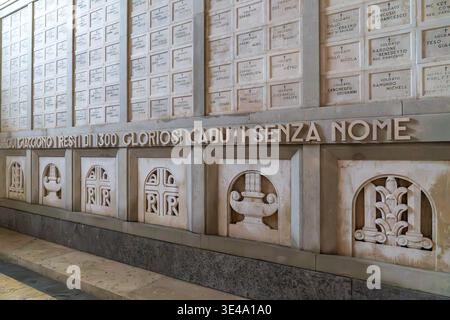 Nahaufnahme der monumentalen Inschrift, die namenlosen Gefallenen am Fagarè Memorial gewidmet ist. Marmorwand mit benannten Nischen oben und symbolischen Basreliefs b Stockfoto