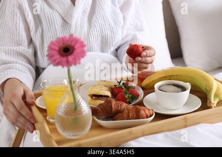 Frau isst köstliches Frühstück im Bett drinnen, Nahaufnahme Stockfoto