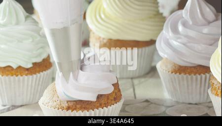 Backen von Cupcakes mit bunten Zuckerguss in einer Küche während der Nachmittagsstunden Stockfoto