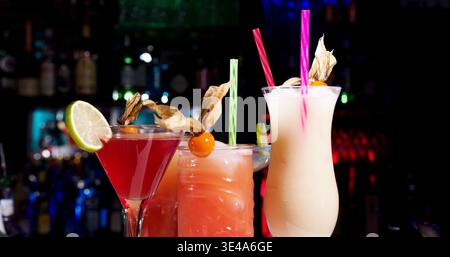 Bunte Cocktails am Bartheken am Abend, die eine Mischung aus Getränken und Beilagen in einem lebhaften Veranstaltungsort präsentieren Stockfoto