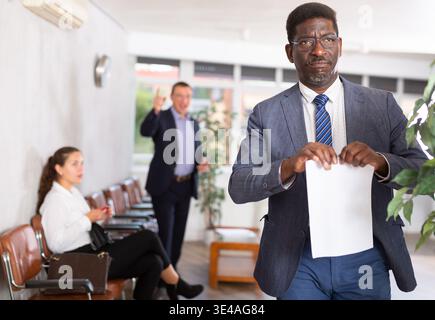 Ein erwachsener Mann wurde mit Dokumenten an der Rezeption verärgert Stockfoto