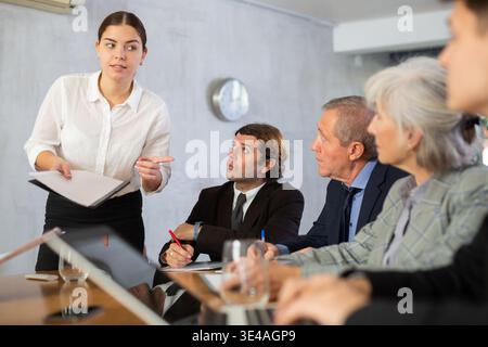 Junge Frau, die mit einem Team im Büro über ein Unternehmensprojekt spricht Stockfoto