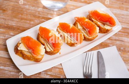 Leckere Sandwiches mit Lachs und Butter auf weißem Teller Stockfoto