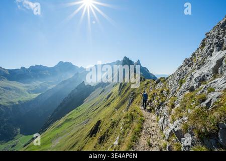 Wanderer auf einem schmalen Pfad entlang eines Bergrückens, der die sonnigen schweizer alpen genießt Stockfoto