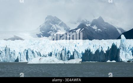 Perito Moreno Gletscher mit zerklüftetem blauem Eis und schneebedeckten Gipfeln unter dramatischen Wolken im Los Glaciares Nationalpark, Patagonien, Argentinien Stockfoto