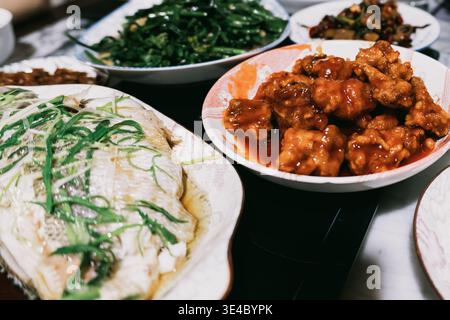 Gedämpfter Fisch mit grünen Zwiebeln, süßsaurem Schweinefleisch und gebratenem Gemüse in einem chinesischen Restaurant Stockfoto