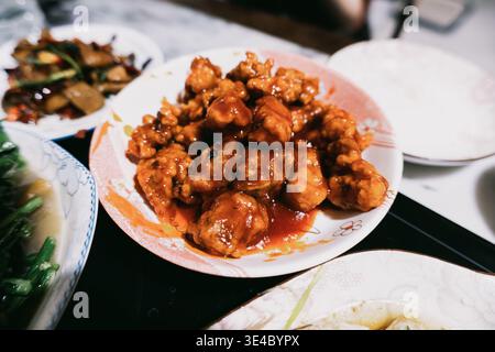 Süß-saures Schweinefleisch mit knusprigen gebratenen Fleischbällchen, serviert auf weißem Teller im chinesischen Restaurant, Stockfoto
