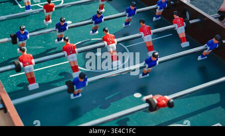 Tischkicker mit roten und blauen Spielern in Aktion an sonnigen Tagen. Stockfoto