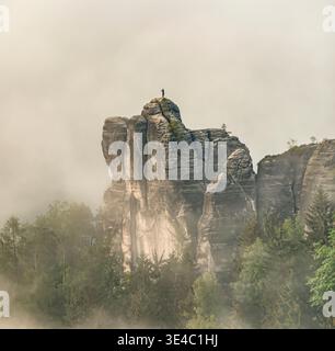 Einsamer Mönchsfelsen im Nationalpark Sächsische Schweiz, Deutschland, dramatische Sandsteinklippen, die sich durch Morgennebel erheben. Stockfoto