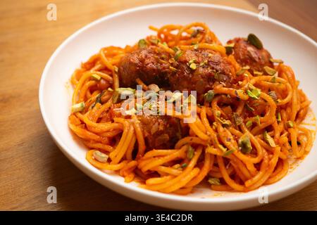 Herzhafte Spaghetti und Fleischbällchen in einer reichhaltigen Tomatensauce, garniert mit frischen Basilikumblättern Stockfoto