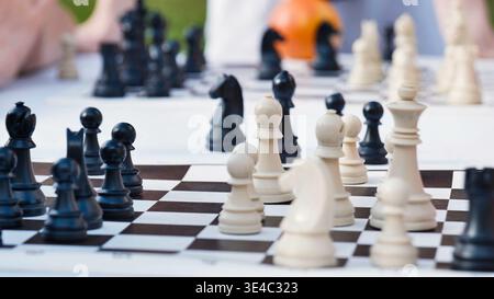 Strategisches Schachspiel mit schwarzen und weißen Figuren auf einem karierten Brett. Stockfoto