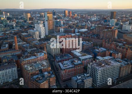 Eine erhöhte Perspektive mit Blick auf das dichte städtische Gefüge von Manchester bei Sonnenaufgang, zeigt die Kreuzung von historischen Mühlen und modernen Gebäuden. Stockfoto