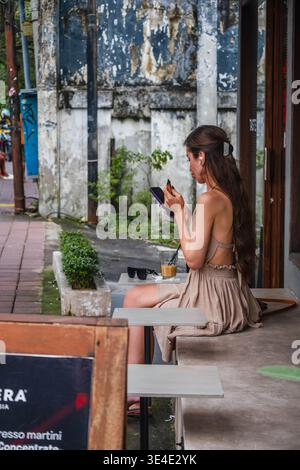 Eine junge Frau, die im Outdoor Cafe ein Smartphone benutzt Stockfoto