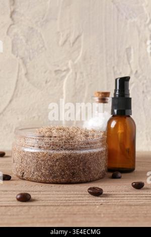 Glas Körperpeeling, Meersalz, ätherisches Öl und Kaffeebohnen auf Holztisch Stockfoto