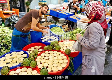 Händler verkaufen frische Waren auf einem geschäftigen Straßenmarkt in Istanbul. Käufer erkunden verschiedene Produkte und interagieren mit Verkäufern. Stockfoto