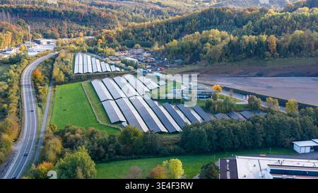 Luftaufnahme: Großes Solarkraftwerk neben einer Straße in der herbstlichen Hügellandschaft Stockfoto