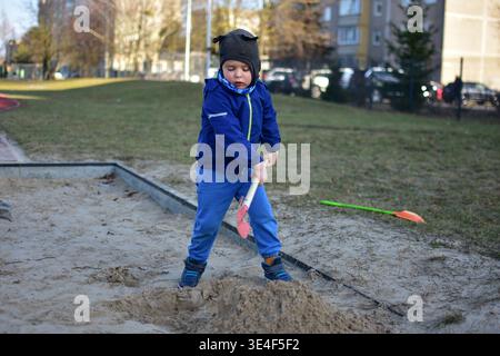 Kinder spielen in Sandkasten, graben Sand mit Schaufel, Outdoor-Spielplatz, Lernen und Entwicklung, lässiger Lifestyle-Moment, natürliches Licht envir Stockfoto