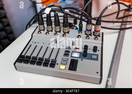Hochwinkelansicht des kompakten Audiomischers, der für die Radio- und Podcast-Produktion verwendet wird. Mehrere XLR- und Klinkeneingänge angeschlossen. Das Gerät verfügt über Schieberegler und Stockfoto