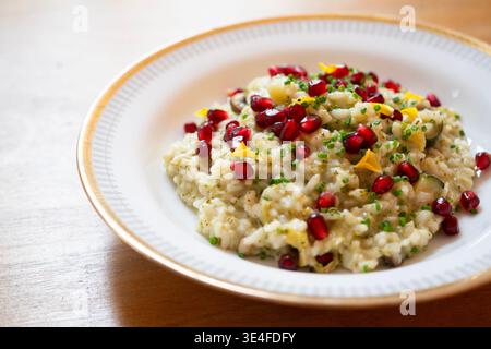 Cremiges Risotto mit Granatapfelkernen und frischen Kräutern, serviert in einer weißen Schüssel Stockfoto