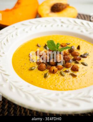 Cremige Kürbissuppe mit Pfirsich, garniert mit gerösteten Kichererbsen und Kürbiskernen Stockfoto