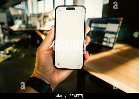 Handheld-Smartphone mit leerem Bildschirm, moderner Büroarbeitsplatz. Closeup Mensch Hand Gerät Display Vorlage Modell digitale Technologie Geschäftsumgebung Stockfoto