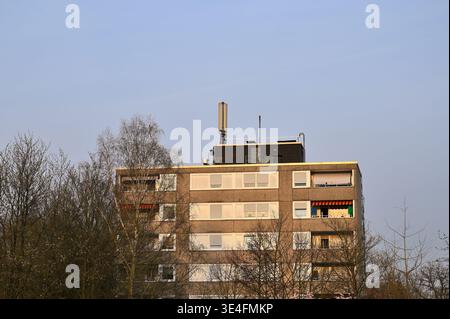 Appartementgebäude mit Zellenturm auf dem Dach vor klarem blauem Himmel Stockfoto