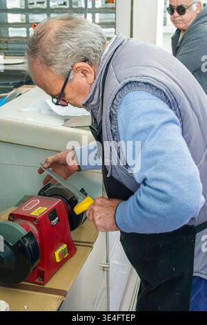Malaga Spanien, Andalusien, El Molinillo Capuchinos, Mercado Municipal de Salamanca, Lebensmittelmarkt in der Nachbarschaft, Mann Erwachsener Senior Worker schärfen Messer elektr Stockfoto
