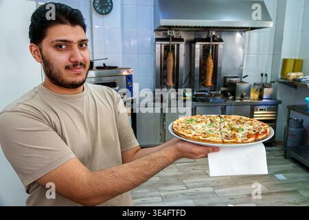 Malaga Spanien, Andalusien, El Molinillo Capuchinos Nachbarschaft, Restaurant Küche Arbeiter Mann Erwachsener nahöstliche Ethnizität hält Pizzateller Essen Serv Stockfoto