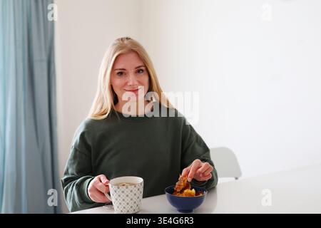 Frau, die Wabenwabe und Kaffeetasse hält, sauberes Essen und einfaches Wohnkonzept. Stockfoto