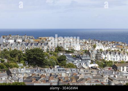 Ein großer Blick aus der Vogelperspektive auf traditionelle Häuser und Dächer in der Küstenstadt St Ives, Cornwall, unter einem blauen Himmel mit dem Ozeanhorizont im Hintergrund Stockfoto