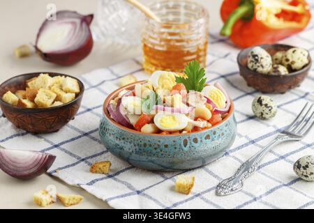 Essen, köstlicher Salat aus Hühnerfilet, Paprika, weiße Bohnen, Wachteleier, Brotcroutons, rote Zwiebeln und Petersilie mit einer Sauce aus Olivenöl, Mustar Stockfoto
