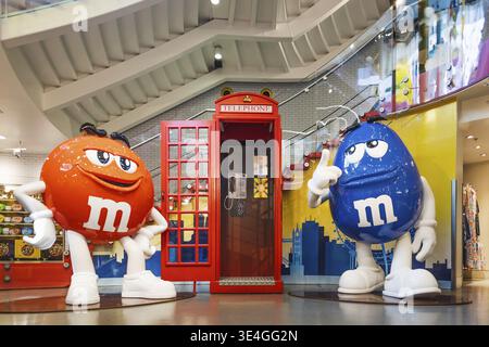 Übergroße rote und blaue M- und M-Statuen an einer klassischen roten Telefonbox im Londoner Flaggschiff-Süßwarenladen, die lustige Markendarstellung und Tourismus veranschaulichen. London Stockfoto