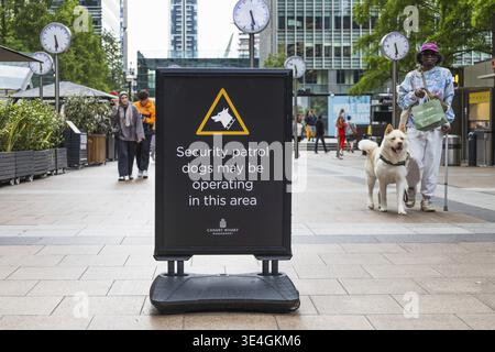 Ein Straßenschild in Canary Wharf warnt vor Sicherheitskontrollhunden in der Gegend. Urbanes Geschäftsviertel mit Fußgängern. London, UK, 16. Juni 2 Stockfoto