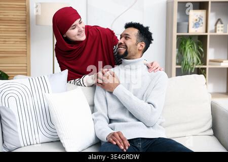 Glückliches muslimisches Paar, das zu Hause die Hände hält Stockfoto