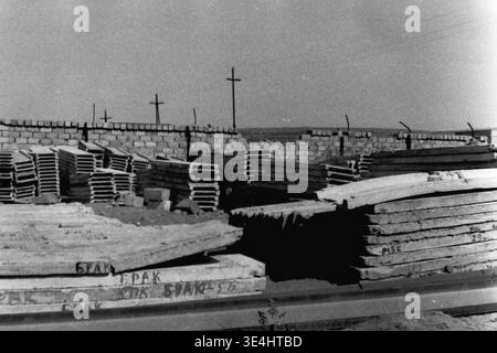Nikolajewka, 1957. Slawjanskaja GRES. Ein Archivfoto eines Freiluftlagers direkt auf der SlavGRES-Baustelle. Schwere Stapel von Betonfertigteilen werden ordentlich gestapelt und können einbaufertig werden. Im unmittelbaren Vordergrund zeigt eine große Betonplatte deutlich den handgeschriebenen kyrillischen Text „BRAK“, der auf einen kritischen Defekt oder eine Ablehnung hinweist. Im Hintergrund sind Holzmasten sichtbar. Dieses Schwarzweiß-Bild dokumentiert Logistik und strenge Qualitätskontrollen und spiegelt das friedliche, hart arbeitende Leben und Bauen im friedlichen Donbass wider. Stockfoto