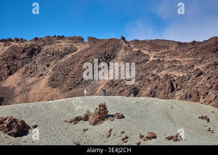 Teide, Teneriffa, 13. Januar 2026, Eine Gruppe von Besuchern spaziert entlang der Wege von ockerem Sand und Basaltfelsen, die sich am Fuße des imposanten Mo erstrecken Stockfoto