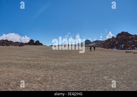 Teide, Teneriffa, 13. Januar 2026, Eine Gruppe von Besuchern spaziert entlang der Wege von ockerem Sand und Basaltfelsen, die sich am Fuße des imposanten Mo erstrecken Stockfoto