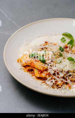 Offene Lasagne mit reichhaltiger Bolognesesauce, Lagen-Nudelblätter, Hackfleisch, cremiger Bechamel, geriebenem Parmesan, Tomaten, frisches Basilikum und aromatische Gewürze Stockfoto