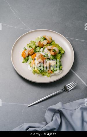 Frischer Salat mit frittierten Tigergarnelen, Orangensegmenten, Avocado, knusprigem Salat und Mikrogrün, garniert mit cremiger Zitronensauce, Frischkäsenoten und Stockfoto