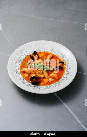 Traditionelle Bouillabaisse, serviert in einer Schüssel mit Garnelen, Muscheln in Muscheln, Tintenfischen in Safran-Tomatenbrühe mit Knoblauch, Zwiebeln, Kräutern Stockfoto