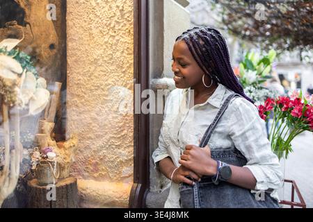 Eine Frau genießt Schaufensterbummel in einer charmanten Straße im Stadtteil Gracia, Barcelona. Der Lifestyle und die lebhafte Atmosphäre betonen das Wesen Stockfoto
