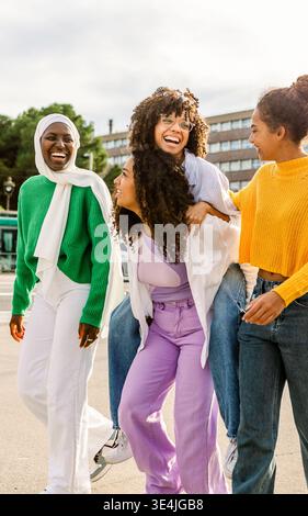 Glückliche, vielfältige Frauen, die draußen gemeinsam spazieren und lachen Stockfoto