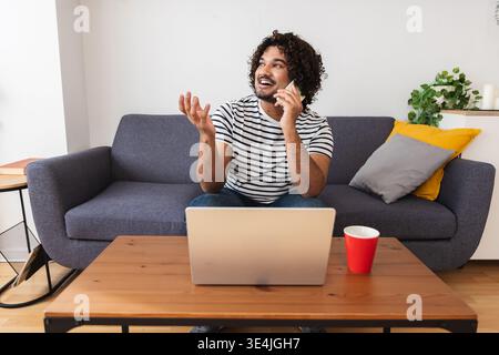 Junger Indianer, der zu Hause mit dem Handy spricht Stockfoto