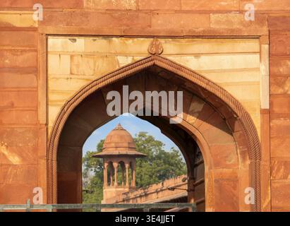 Agra, Indien, 20.02.2020. Detaillierter Blick auf einen historischen roten Sandsteinbogen, der eine traditionelle Kuppelsteinstruktur umrahmt. Stockfoto