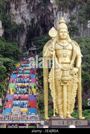 Statue des Hindugottes, Murugan, Batu Caves, Gombak, Selangor, in der Nähe von Kuala Lumpur, Malaysia. Touristen klettern die mehrfarbigen Stufen zum Many Hind Stockfoto