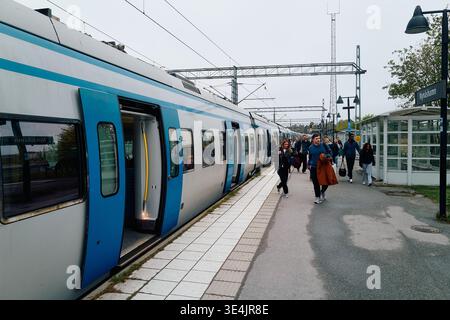 Ein Pendlerzug mit Leuten, die da rauslaufen. Der Zug ist blau und weiß. Nynashamn, Stockholmer County, Schweden, 9. Mai 2025. Stockfoto